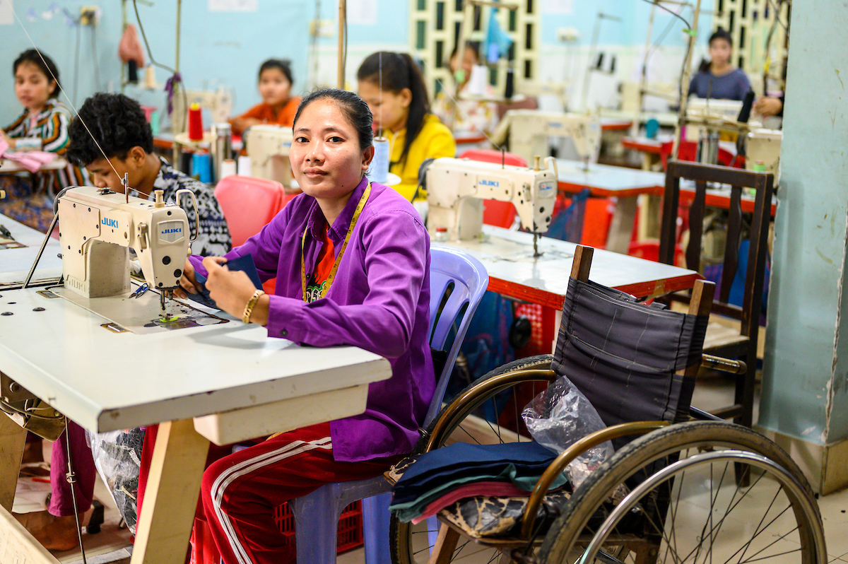 Bilde av kvinner i arbeid i Kambodsja, kvinne i rullestol i sentrum