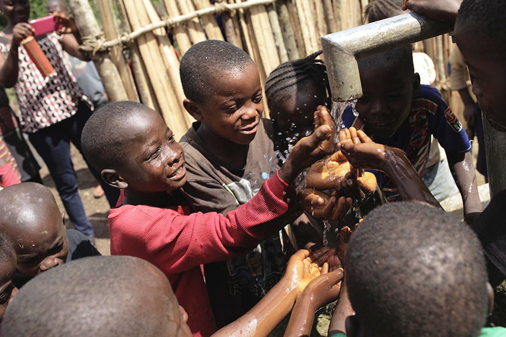 Barn i en landsby i Liberia som vasker hendene i nybygget brønn